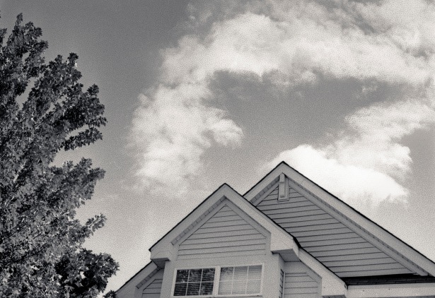 Black and white film image of house with reticulated sky